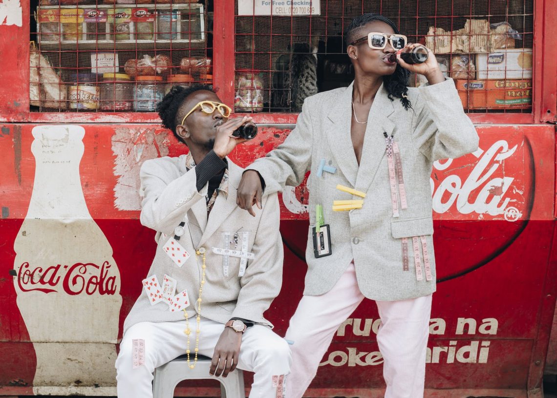 two person drinking coca cola next to a kiosk