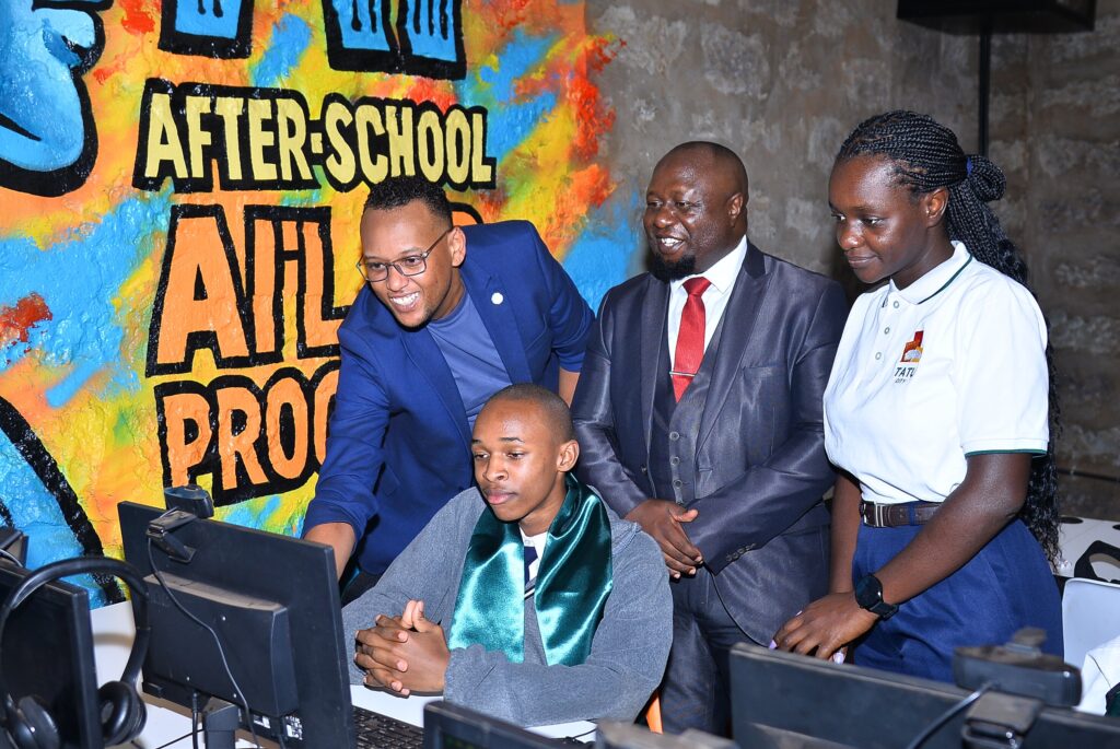 (l-r) Robin Njuno, Managing Executive, Learning & Development, CCI Global; John Kiria, Director ICT, E-commerce and entrepreneurship division, State Department for ICT and digital economy; and Linda Nyaseda, Head of City Management and DCC, Tatu City look on as Nathaniel Kang'ethe, a student at Tatu Primary School